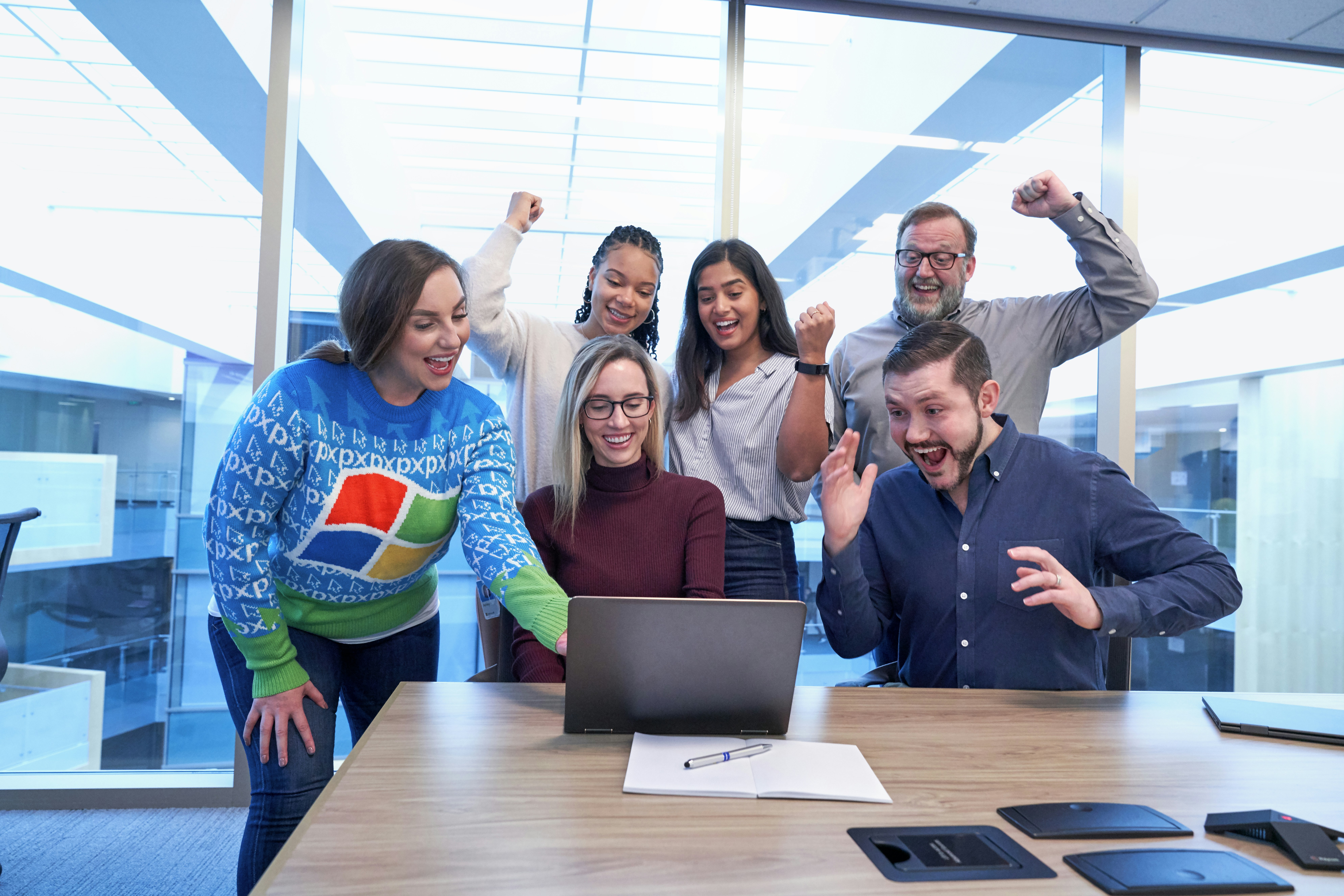 Happy team members celebrating success with high-fives in bright modern office space